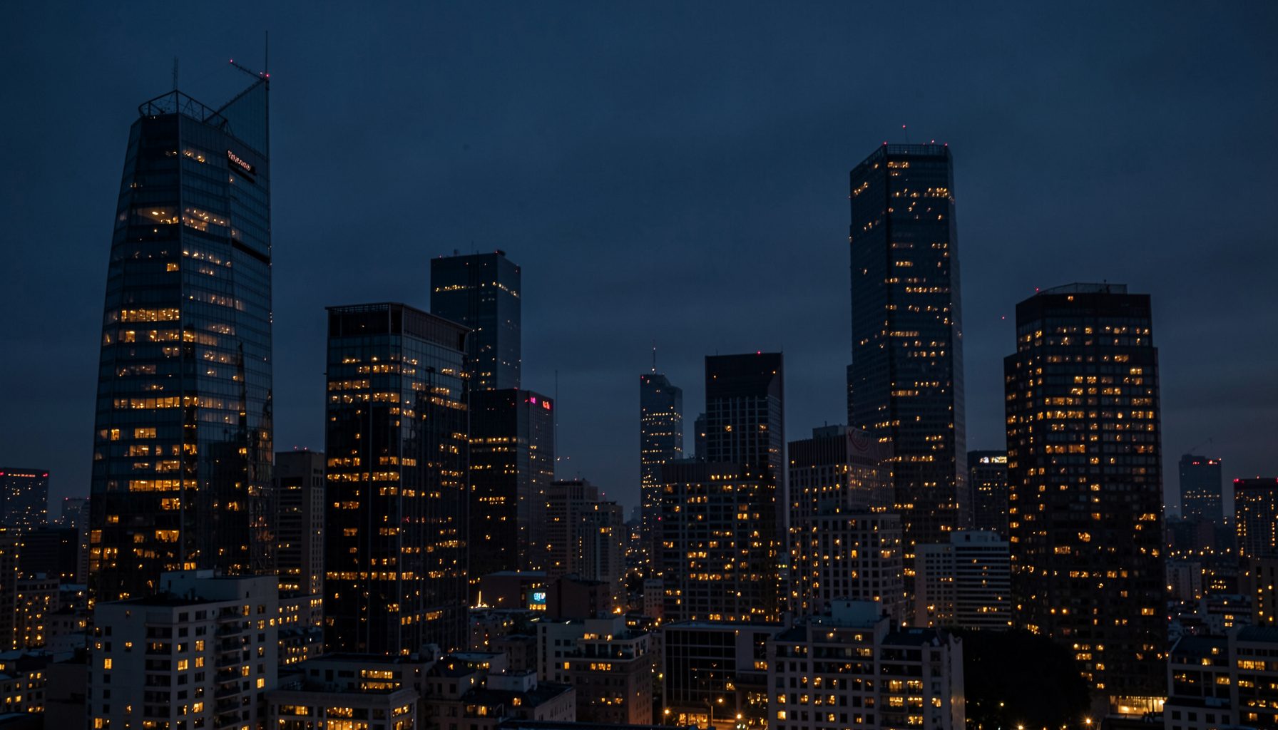 A dark, atmospheric city skyline at twilight with deep navy and charcoal tones, accented by warm amber lights reflecting off glass towers, conveying a polished metropolitan magazine mood.