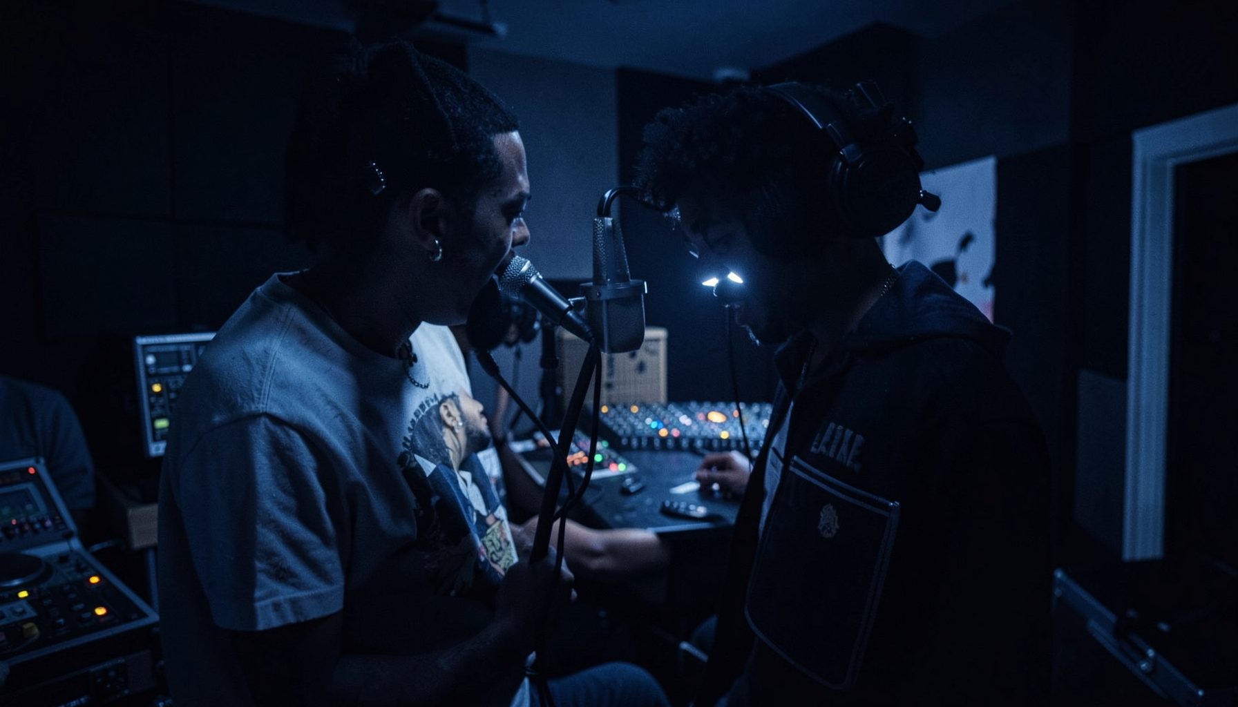 A moody, low-lit studio scene with deep indigo and charcoal hues, evoking the energy of a hip-hop recording session.